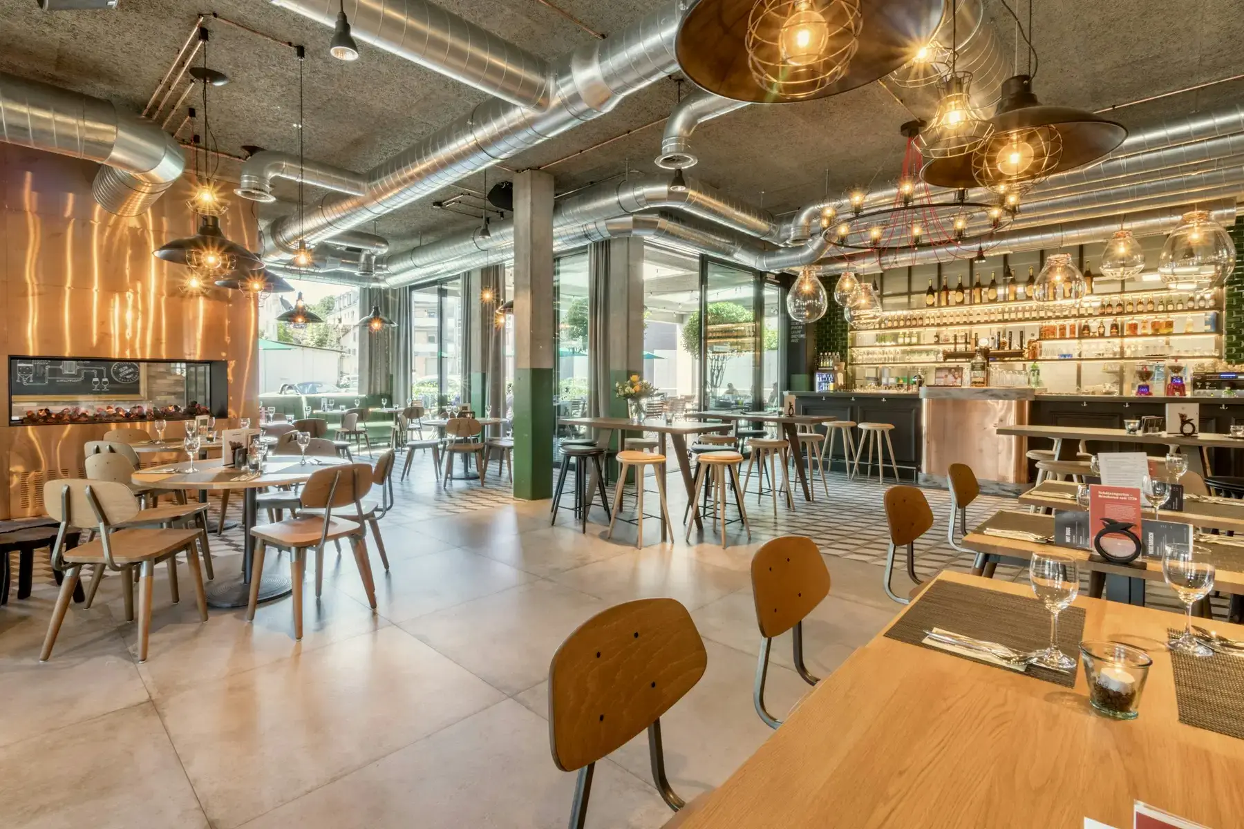 Restaurantzaal bij daglicht met gedekte tafels en een open keuken op de achtergrond